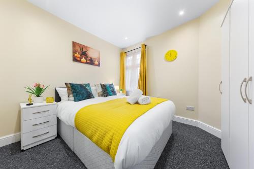 a bedroom with a bed with a yellow blanket at Stylish & Modern 2-Bedroom London Hideaway - King Bed- Sleeps 6 - Parking Available - Instant Book - 20 Percent Off Long Stays! in Barnet