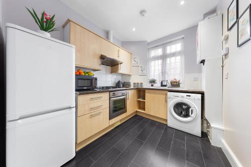 a kitchen with wooden cabinets and a washer and dryer at Stylish & Modern 2-Bedroom London Hideaway - King Bed- Sleeps 6 - Parking Available - Instant Book - 20 Percent Off Long Stays! in Barnet