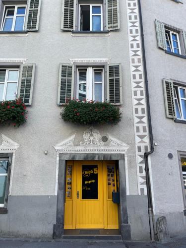 a building with a yellow door and flowers on it at Haus zum Rütli in Chur
