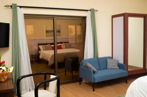 a room with a blue chair and a bedroom at Hotel le Pelican in Lomé