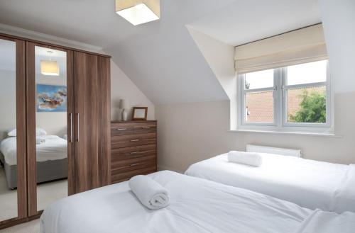 a white bedroom with two beds and a window at Large detached Cambridgeshire Countryside Home in Wilburton