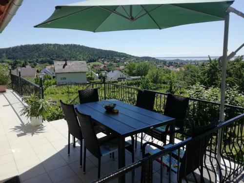 a table and chairs on a balcony with an umbrella at Harmónia Vendégház in Vonyarcvashegy