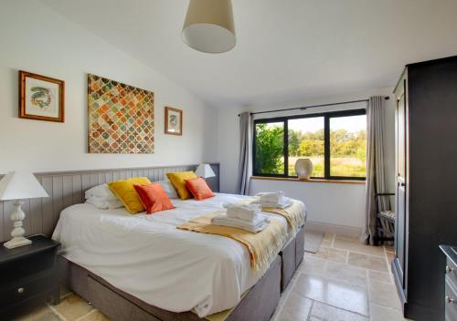 una camera da letto con un grande letto con cuscini arancioni e gialli di Long Barns a Briston