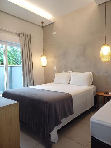 a bedroom with a large white bed with white pillows at Casatua Pousada in Juquei
