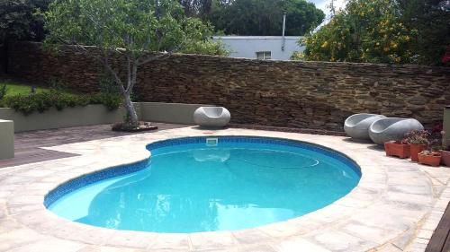 a swimming pool in a yard with a stone wall at Villa Limonicella in Barrydale