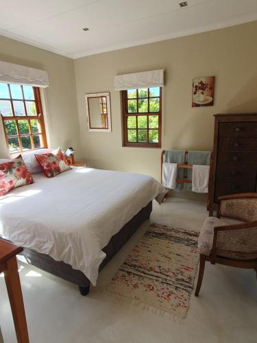 a bedroom with a large bed and a chair at Villa Limonicella in Barrydale