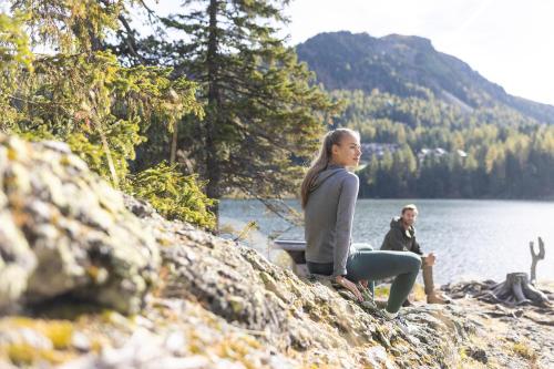 a woman sitting on a rock next to a lake at Hotel Hochschober in Turracher Hohe