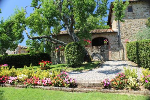 a garden with flowers in front of a building at Arco al Poggio - Arceno Rentals Club in San Gusmè