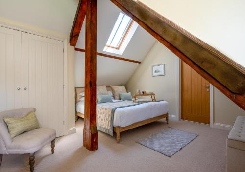 a bedroom with a bed and a chair in a attic at Boat Barn Cottage 6 in Blakeney