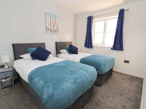 a bedroom with two beds with blue pillows at THE Beach House in Prestatyn