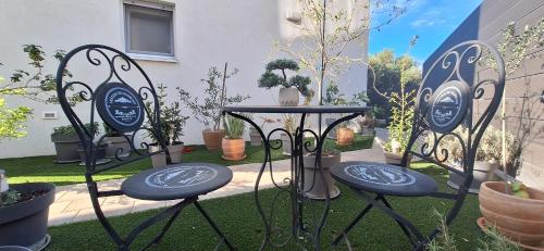 two chairs and a table in a yard with potted plants at Apartman Barry in Primošten