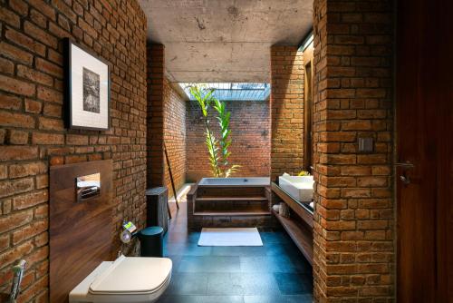 a brick bathroom with a bath tub and a toilet at Taru Villas Maia - Habarana in Habarana