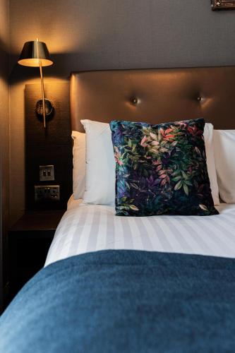 a bed with a colorful pillow on top of it at The House on Warwick in London