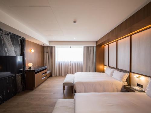 a hotel room with two beds and a flat screen tv at Hôtel de Ľeau in Anping