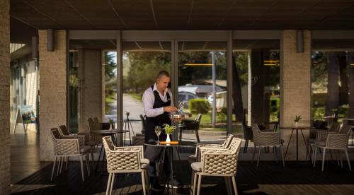 um homem de pé numa mesa num restaurante em Maistra Camping Porto Sole Pitches em Vrsar