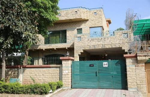 a house with a green garage door in front of it at Islamabad Lodges in Islamabad