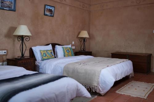 1 dormitorio con 2 camas y 2 lámparas en la pared en Kasbah Zitoune en Ouarzazate