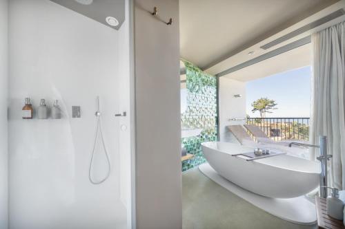 a bathroom with a white tub and a sink at Immerso Hotel, a Member of Design Hotels in Ericeira