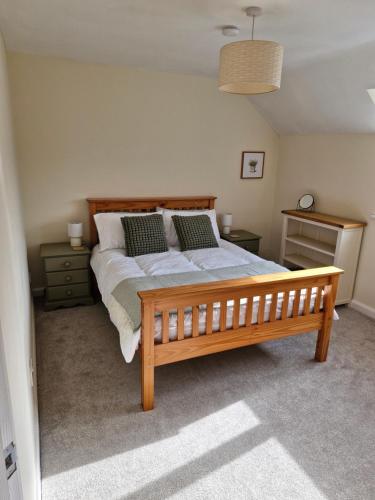 Un dormitorio con una gran cama de madera con almohadas en Rosemary Cottage, Uley, Gloucestershire en Uley