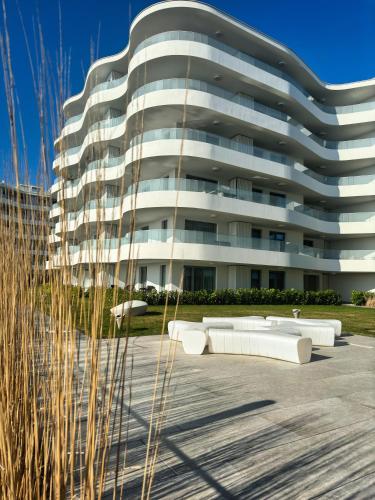 a large white building with benches in front of it at Rogowo Pearl Apartamenty in Rogowo
