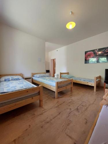 three beds in a room with wooden floors at Akácliget Vendégház és Major in Ófehértó