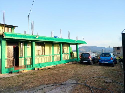 a green house with cars parked in front of it at GREEN HILLS in Cherrapunji