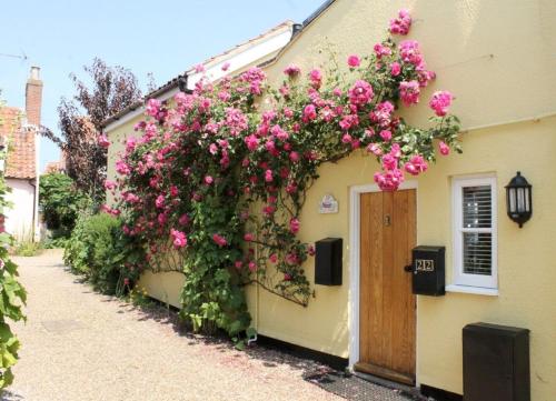 a building with pink flowers on the side of it at Pilot Cottage in Southwold