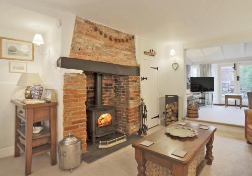 a living room with a brick fireplace and a table at Pilot Cottage in Southwold