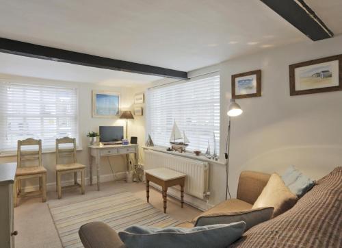 a living room with a couch and a table and a desk at Pilot Cottage in Southwold
