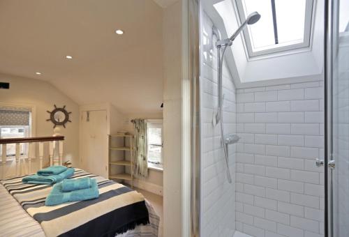 a bedroom with a shower and a bed with blue towels at Pilot Cottage in Southwold