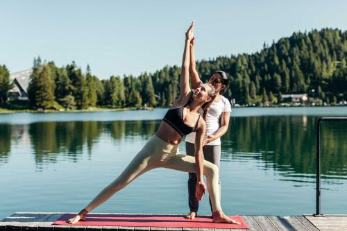 a man and a woman doing yoga on a dock by a lake at Hotel Hochschober in Turracher Hohe