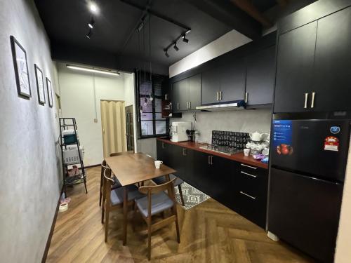 une cuisine avec des armoires noires et une table en bois dans l'établissement Rumah Hijau Homestay, à Alor Setar