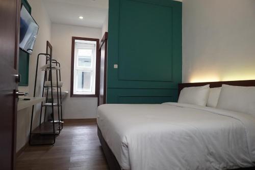 ein Schlafzimmer mit einem Bett und einer grünen Wand in der Unterkunft Riche Heritage Hotel in Malang