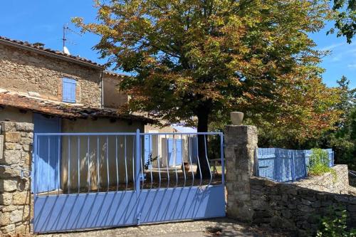 a blue gate in front of a house with a tree at Splendide vue - Maison campagne in Monoblet