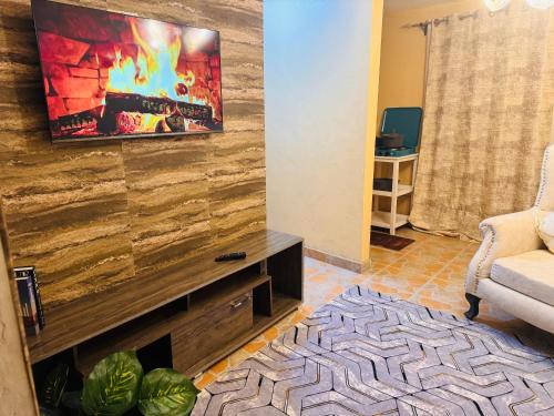 Haven homes في Kiambu: غرفة معيشة مع موقد وتلفزيون على الحائط