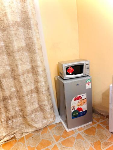 a microwave on top of a refrigerator next to a curtain at Haven homes in Kiambu