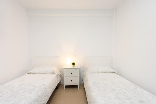 two beds in a bedroom with white walls at Home2Book Pleasant & Design Apt Santa Cruz Center in Santa Cruz de Tenerife