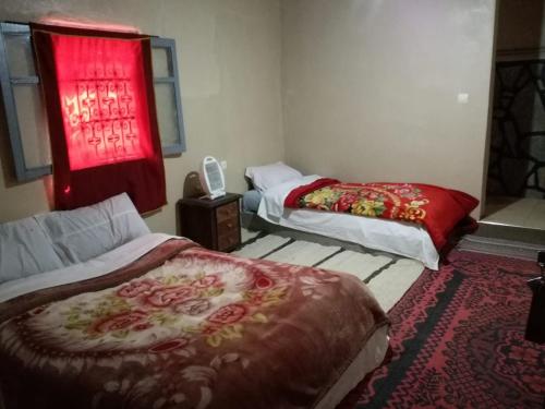 a room with two beds and a red window at Riad Bouchra in Tamtetoucht