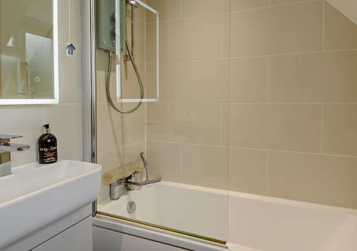 a white bathroom with a shower and a sink at Dolphin Cottage in Wiveton