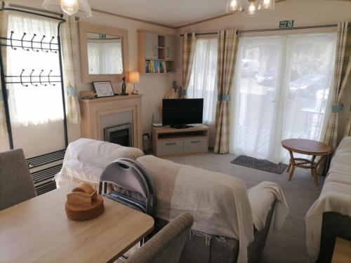 uma sala de estar com um sofá e uma televisão em The Willows - 3 bedrooms with enclosed decking em Fairlight