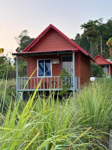 a red house with a porch in a field of grass at Maloop Cafe Bungalow in Koh Rong Island
