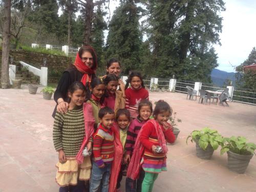 a woman and a group of children posing for a picture at The Hermitage Kanatal in Kanatal