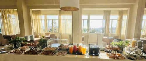 a breakfast table with food on it in a room with windows at B&B Via Mare in Milano Marittima