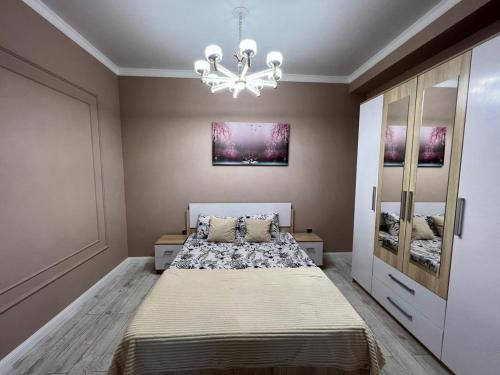 um quarto com uma cama grande e um lustre em Комфортная квартира в ЖК ГРИН ПЛАЗА em Aktau