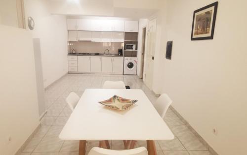 una mesa y sillas blancas en una cocina blanca en RoofTop Apt en Praia