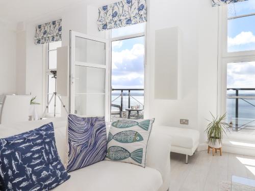 uma sala de estar com um sofá branco e janelas em Bay Sea View em Torquay