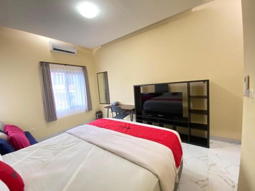 a bedroom with a bed and a flat screen tv at RedDoorz Syariah at Jitu Guest House Purwokerto in Purwokerto