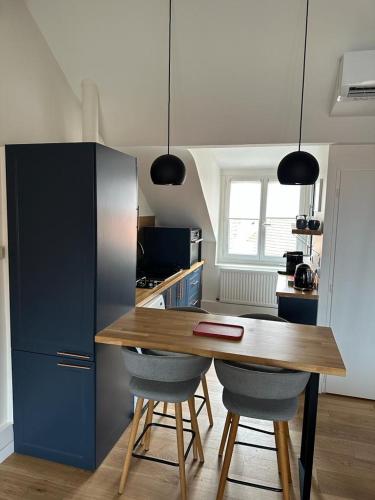 une cuisine avec une table en bois et des armoires bleues dans l'établissement Superbe appartement plein centre de Biarritz, à Biarritz