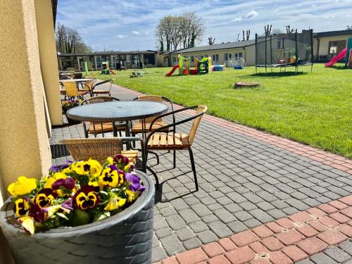 een terras met een tafel, stoelen en bloemen bij Ośrodek rodzinny "Pod Wydmami" PRZY PLAŻY , PLAC ZABAW , ROWERY in Sarbinowo