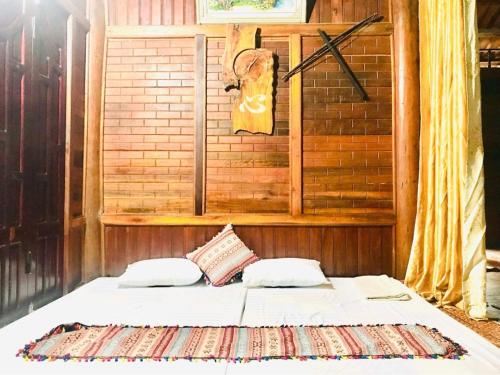 1 cama con 2 almohadas y pared con en Homestay Minh Ngoc, 